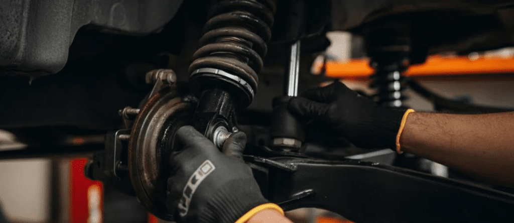 Mechanic inspecting vehicle suspension system